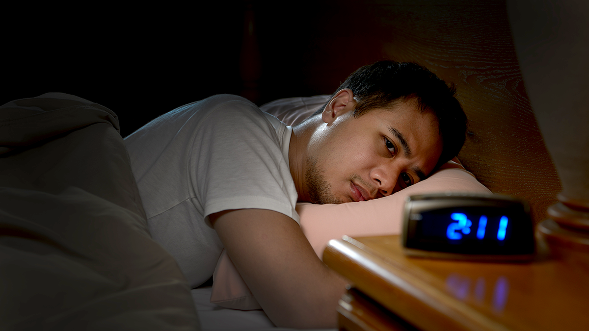 The man is awake in bed late at night